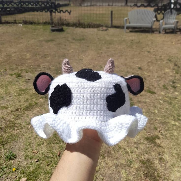 a crocheted cow hat is being held by a hand