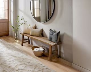 a wooden bench sitting under a round mirror