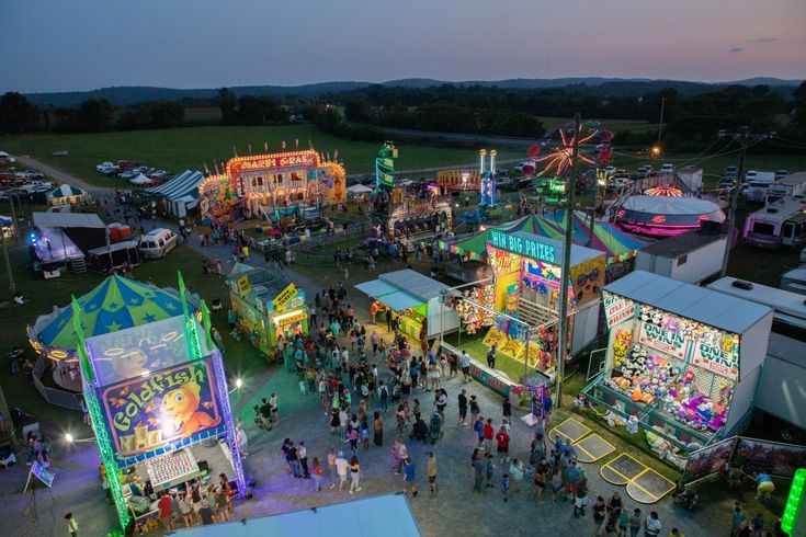 an aerial view of the fairground at night with people standing around and riding on rides