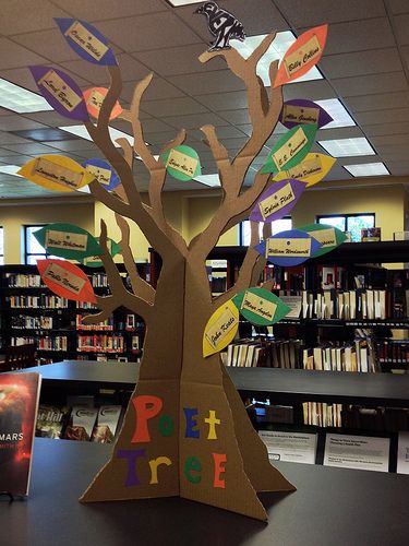 a tree made out of cardboard sitting on top of a table in front of bookshelves