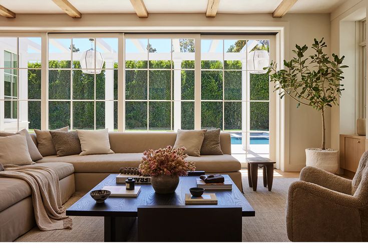 a living room with couches, chairs and a coffee table in front of large windows