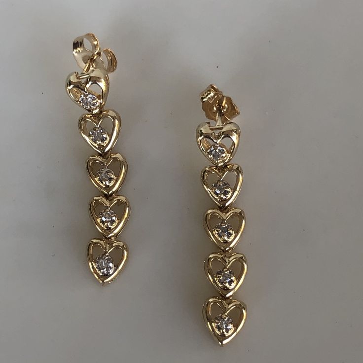 These are adorable heart drop earrings with diamonds set in each little heart. They have a sturdy pushback closing and are not super heavy on the ear. The are slightly over 1 inch in length. They weigh 4.16 grams total weight. The diamonds weight approximately.08ct total. With any pre-owned/Vintage/Antique items, it is common to have some wear, As we inspect each piece of our jewelry, we make sure the wear and tear is acceptable within industry standards FOLLOW US TO SEE MORE PHOTOS OF OUR JEWEL Vintage Heart Charm Earrings For Anniversary, Vintage Gold Heart Dangle Earrings, Vintage Gold Heart Earrings For Valentine's Day, Vintage Heart Charm Earrings For Valentine's Day, Valentine's Day Heart-shaped Diamond Earrings, Gold Bar Earrings, Diamond Dangle Earrings, Heart Drop Earrings, Diamond Anniversary