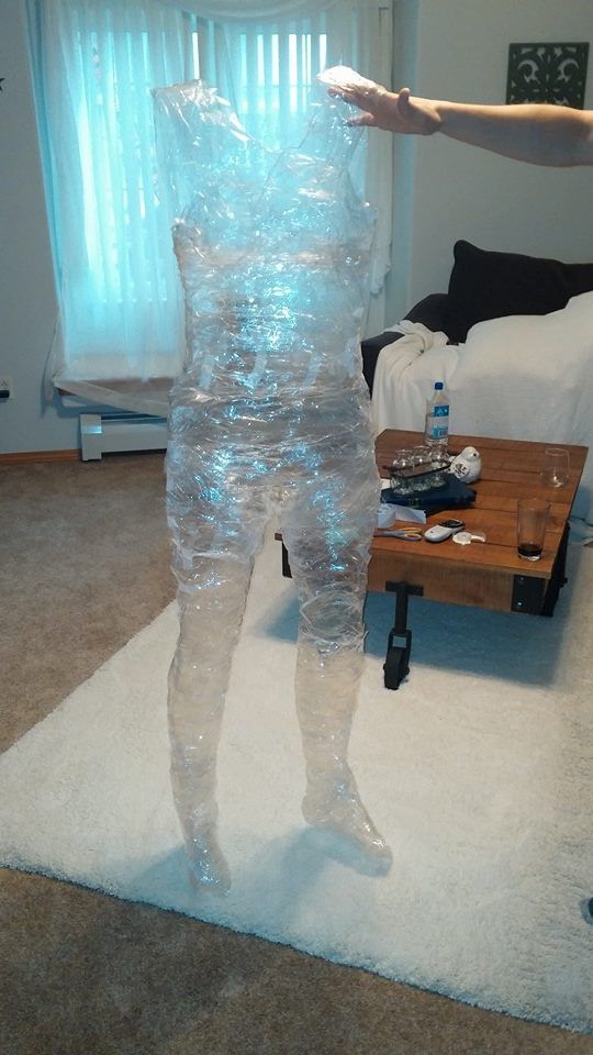 a person standing in a living room with plastic wrapped around their body