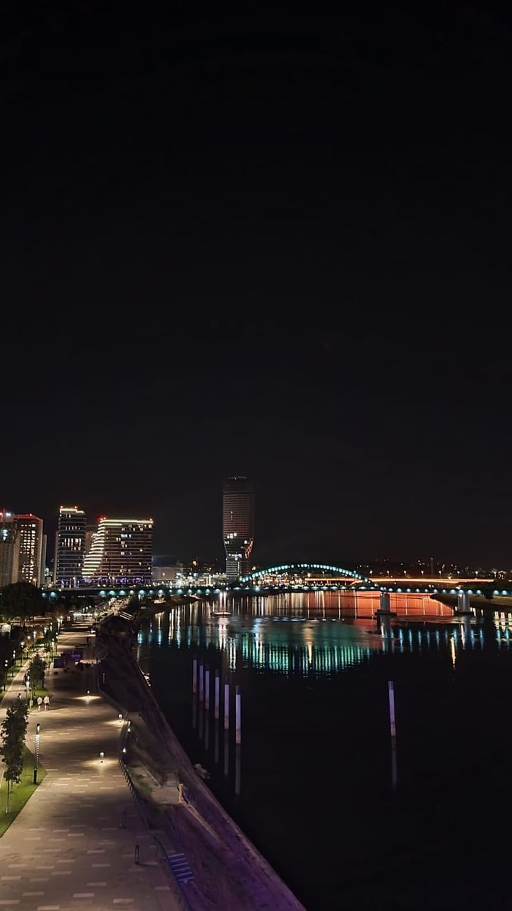 the city is lit up at night by the water