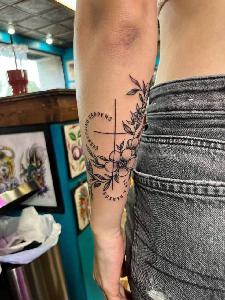 a woman's arm with a compass and flowers tattoo on the left side of her body