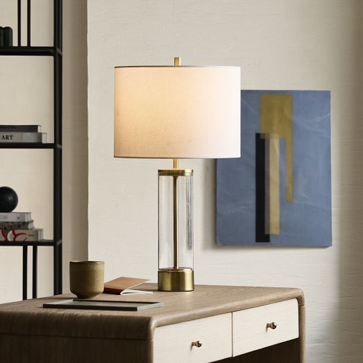 a table lamp sitting on top of a desk next to a book shelf with books