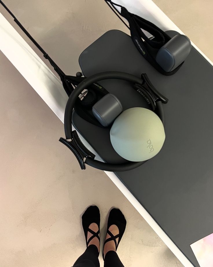 a pair of black shoes standing on top of a skateboard next to a person's feet