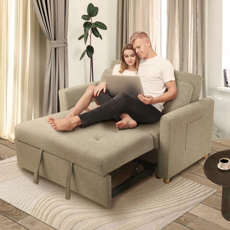 a man and woman sitting on a couch using a laptop