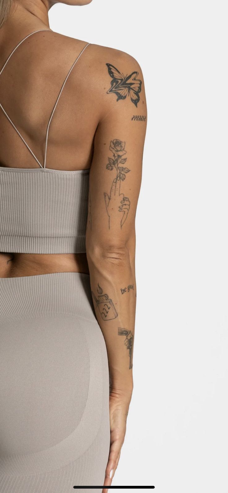 the back of a woman's body with tattoos on her arm and shoulder,