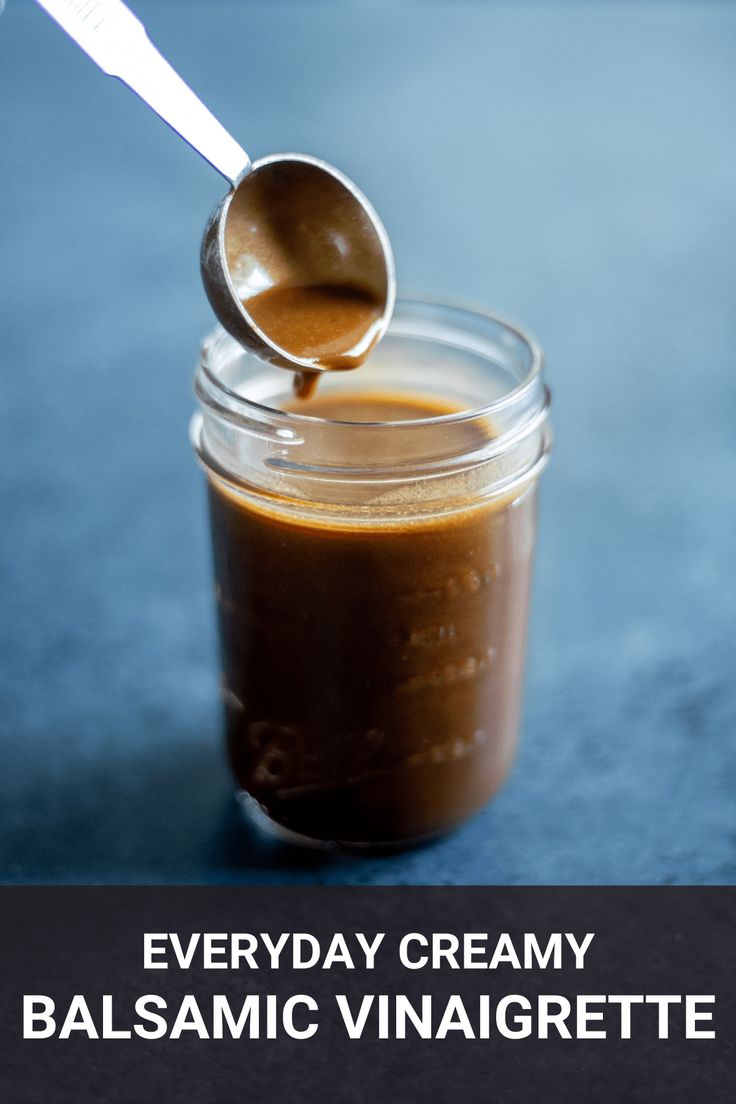 there is a spoon in a glass jar filled with balsamic vinaigrette