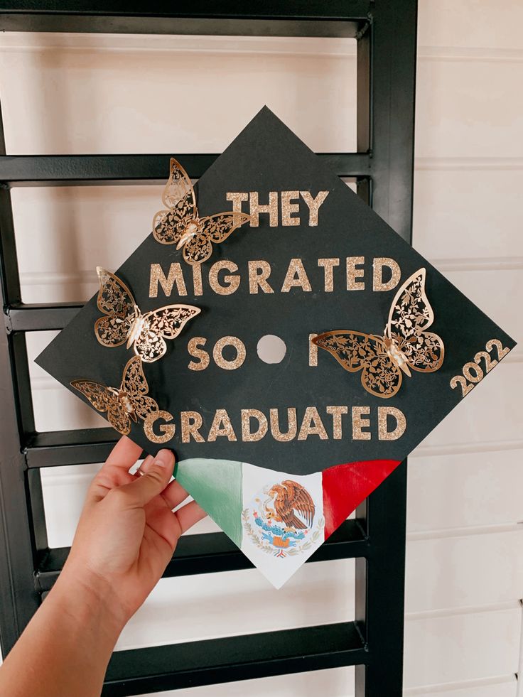 a person holding up a graduation cap that says they migrate so i graduated in mexico