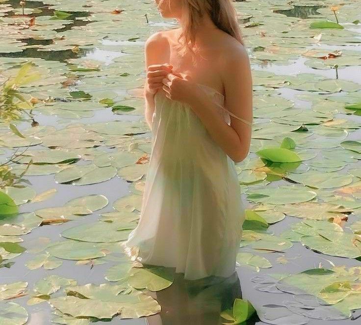 a woman is standing in the water with lily pads