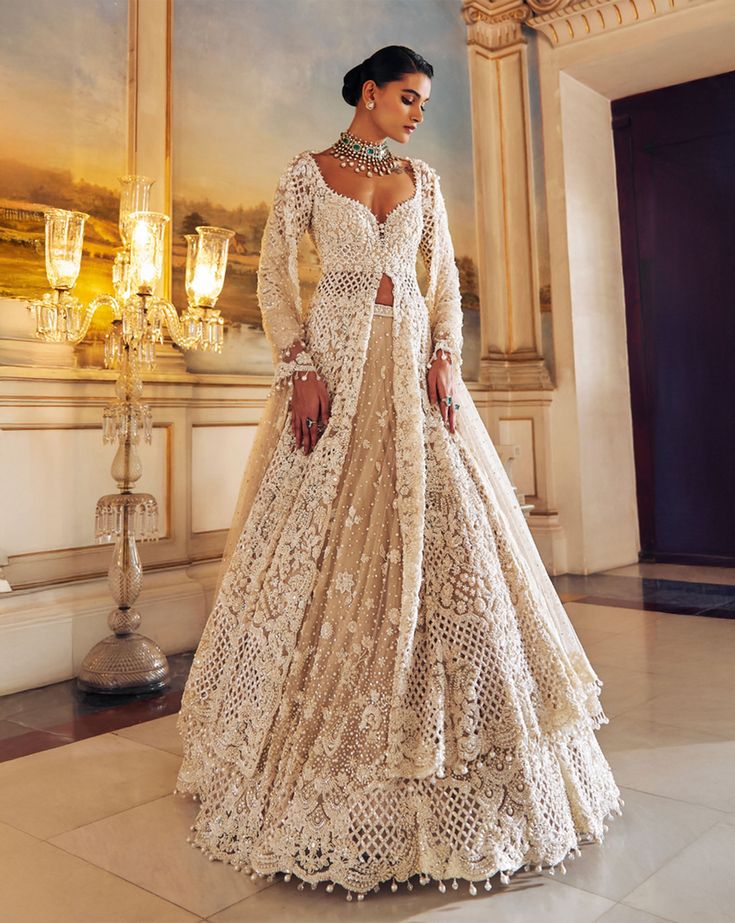 This jacket lehenga set features intricate pearl embroidery interspersed with delicate cut work on a nude base. The full sleeve jacket shows pearl tassels at sleeve hem and is paired with matching embroidered lehenga. The scalloped dupatta shows pearl drops.From Seema Gujral's Falaknuma collection. DELIVERY TIMEPlease allow 8-12 weeks for your outfit to arrive. FABRIC DETAILSNet Professional cleaning only. Jacket And Lehenga, Designer Cream Anarkali Set With Long Sleeves, Elegant Off White Choli With Resham Embroidery, Elegant Long Sleeve Anarkali Set With Sheer Dupatta, Elegant Off-white Choli With Zari Work, Elegant Off White Lehenga With Resham Embroidery, Elegant Semi-stitched Off White Choli, Off White Long Sleeve Sets With Sheer Dupatta, Elegant Off White Choli With Zari Work