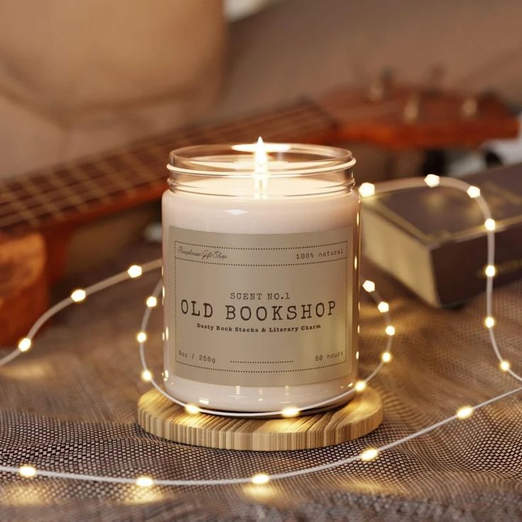 a candle sitting on top of a wooden table next to a string of lights and a guitar