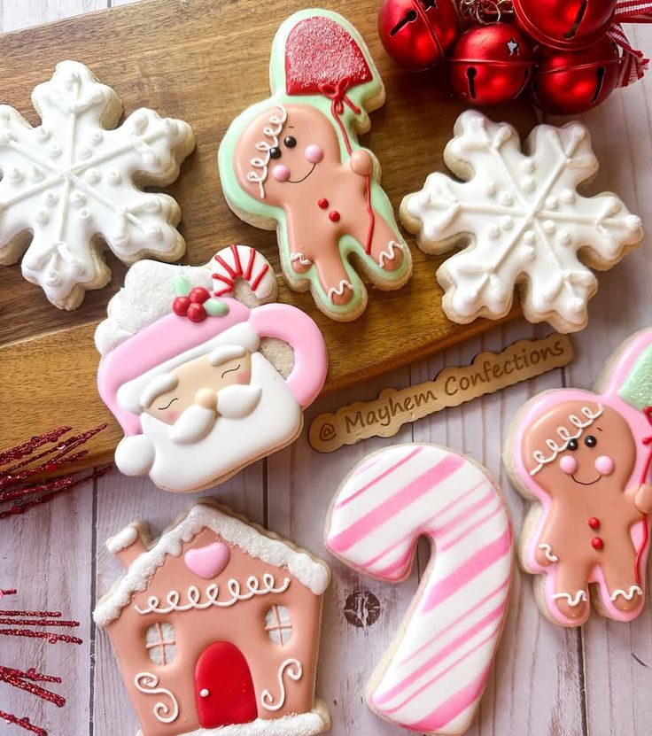 decorated cookies are arranged on a wooden board next to christmas decorations and candy canes