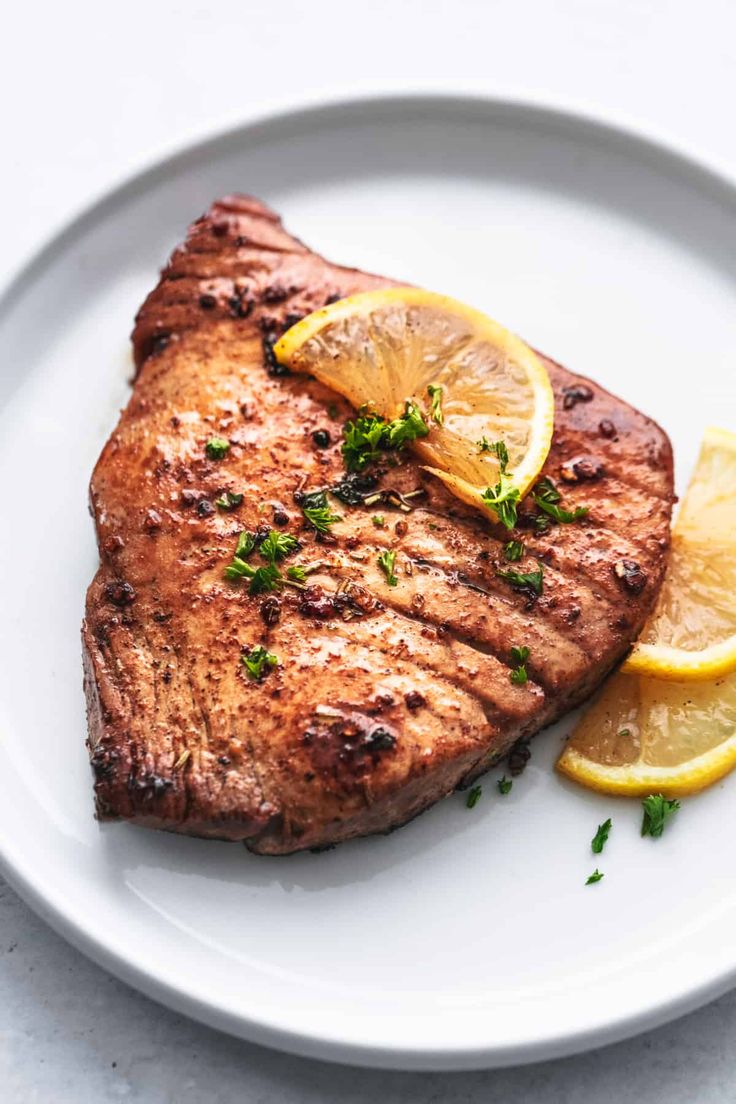 a white plate topped with meat and lemon slices