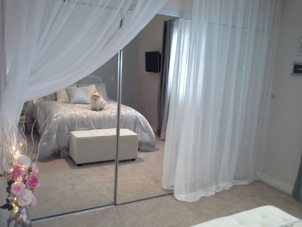 a bedroom with a mirrored door and white curtains