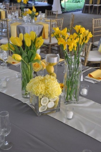 yellow flowers are in vases on the table at a wedding reception with white linen