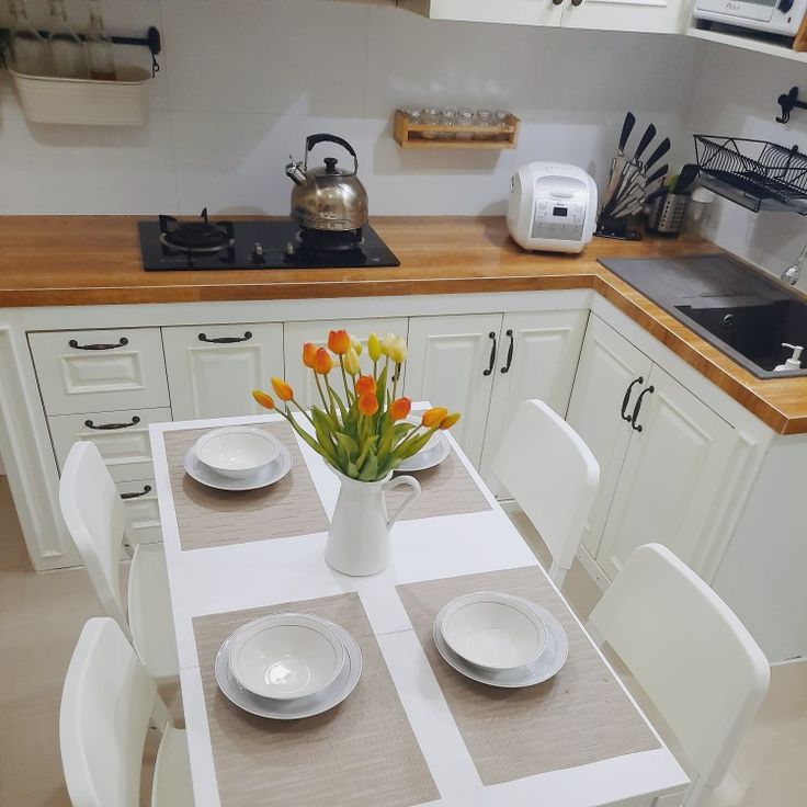 a kitchen table with plates and flowers in a vase on the counter top next to an oven