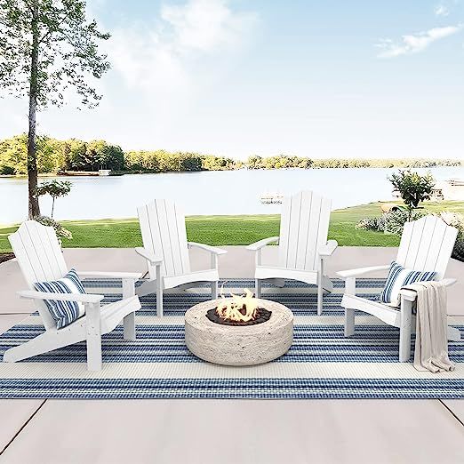 a fire pit surrounded by white chairs on a blue and white striped rug in front of a lake