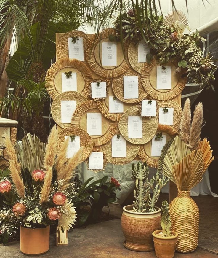 there are many potted plants in front of a wall with pictures on it and place cards attached to the planters