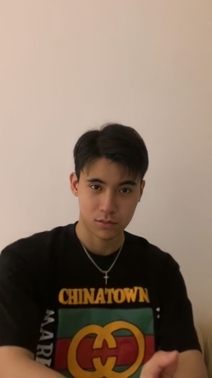 a young man wearing a black shirt with the word chinatown on it and a gucci logo across his chest