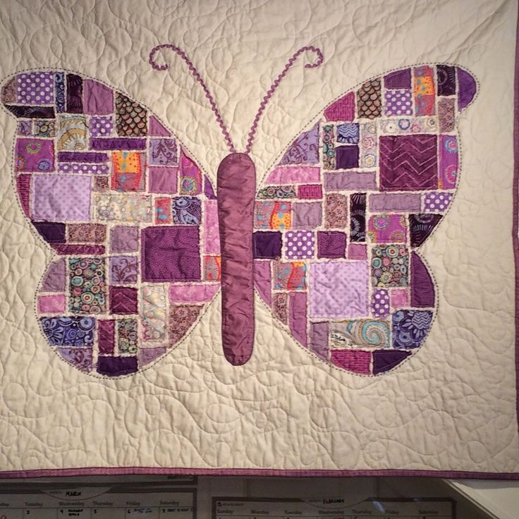 a quilted butterfly is hanging on the wall