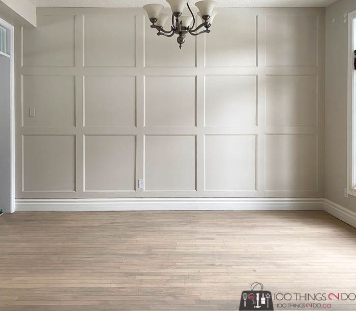 an empty living room with white walls and wood flooring in the center is a chandelier