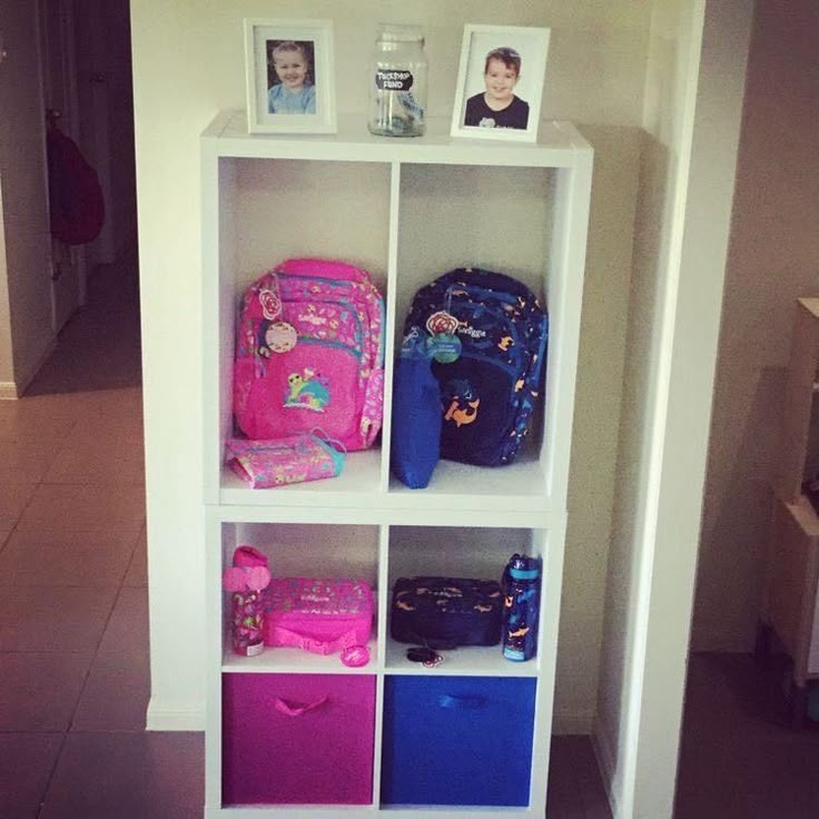 a white book shelf filled with lots of colorful bags and backpacks on top of it