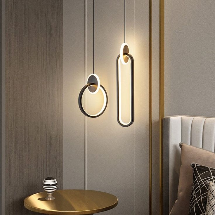 two lights hanging from the side of a wall next to a table with a pillow on it