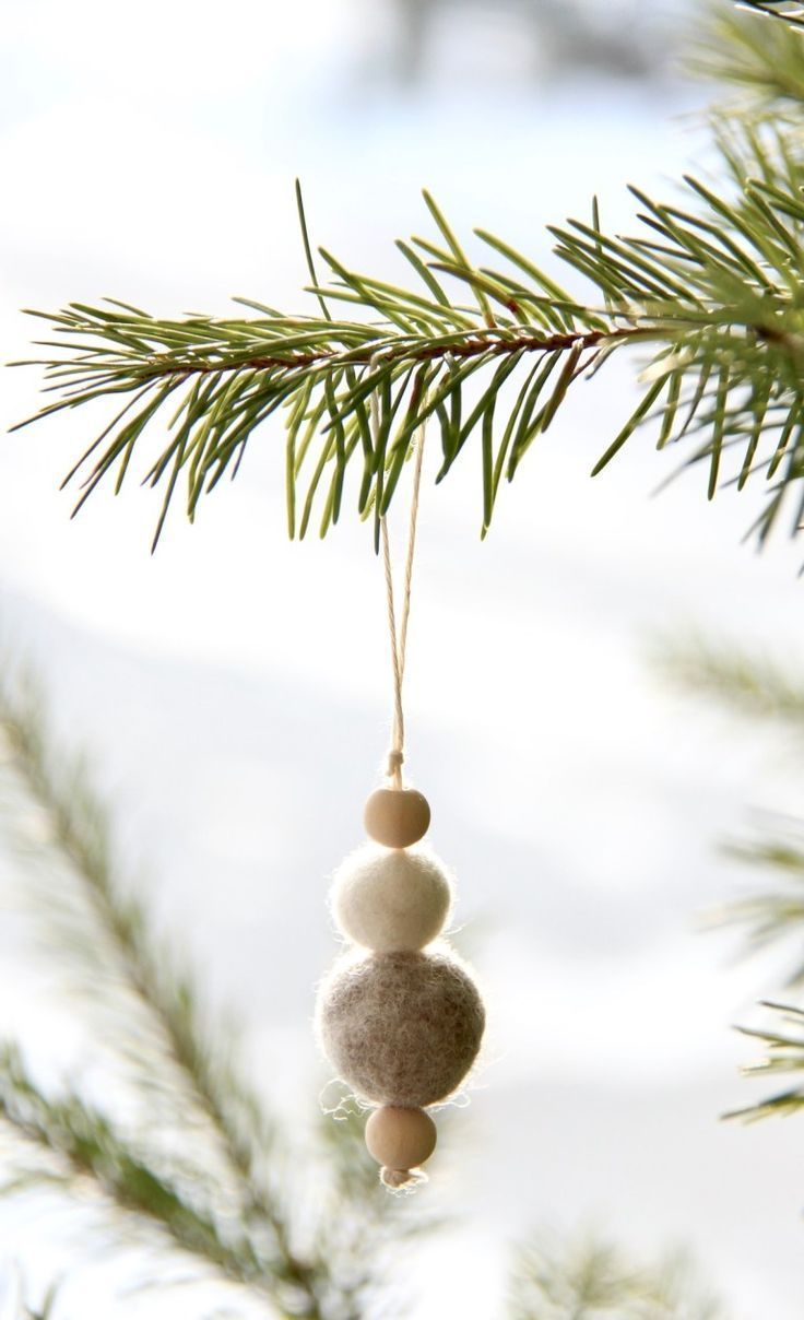 a christmas ornament hanging from a pine tree with snow on the ground in the background