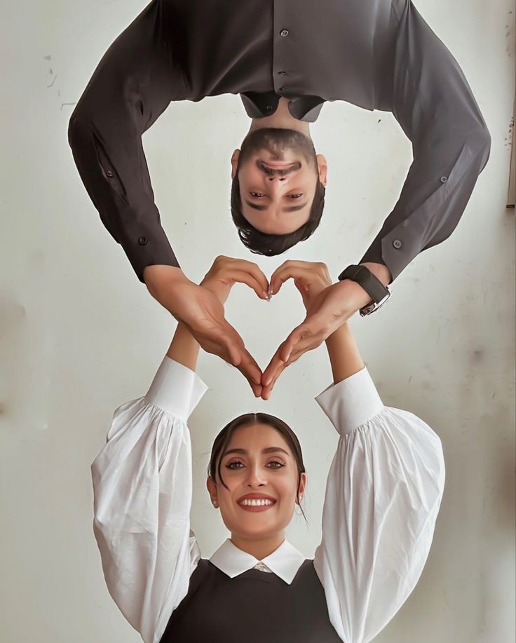 two people standing in the shape of a heart with their hands on top of each other