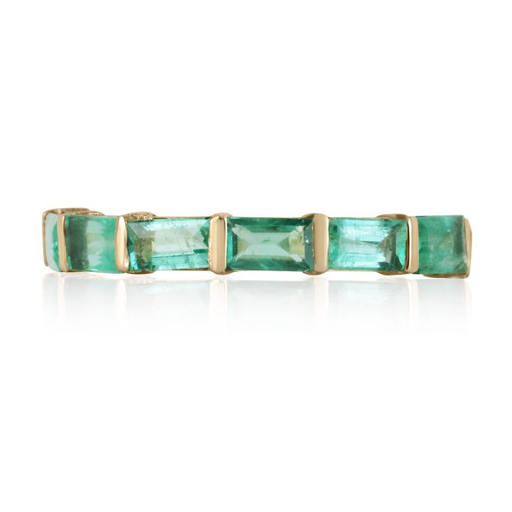 an emerald green tourmaline ring with gold accents on the sides and four rectangular cut stones