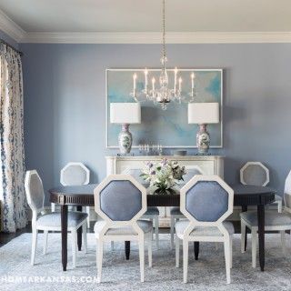 an elegant dining room with blue walls and white chairs, chandelier and table