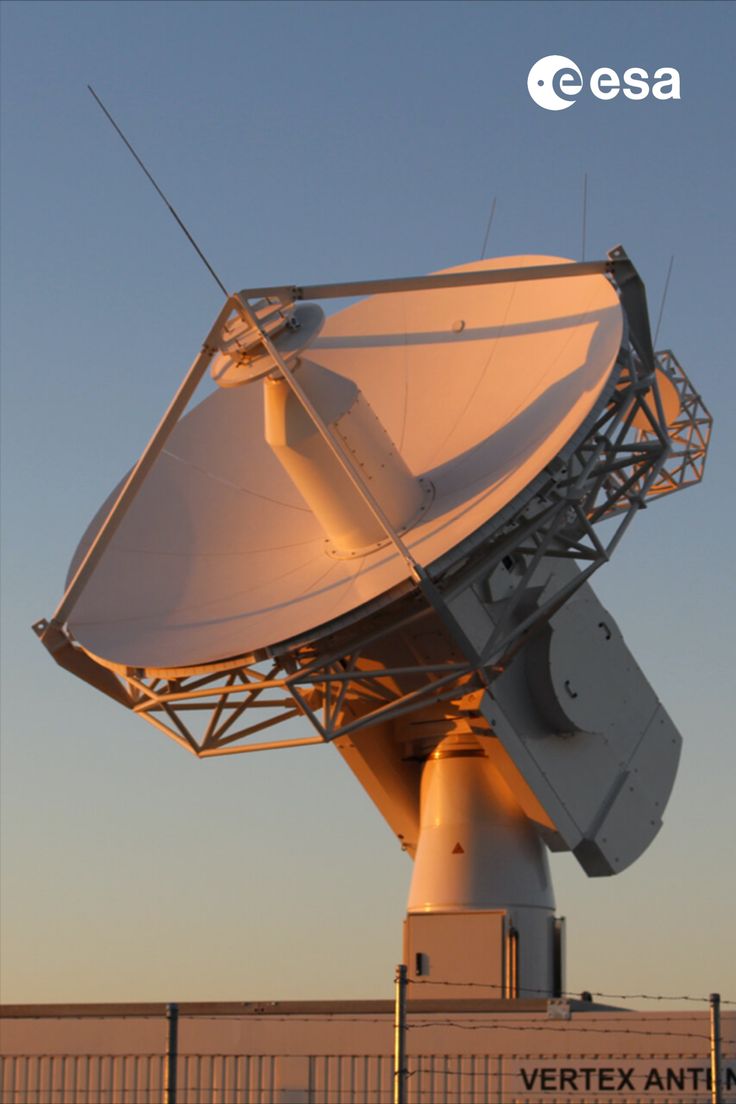 a very large white satellite dish sitting on top of a metal fenced in area