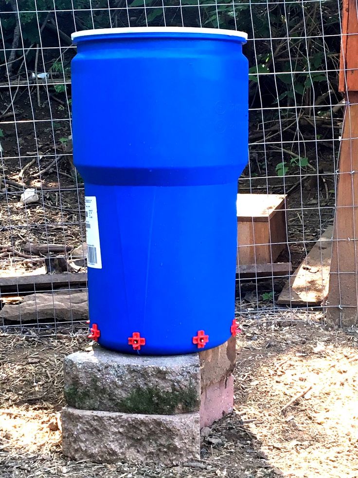 a large blue barrel sitting on top of a cement block in front of a wire fence