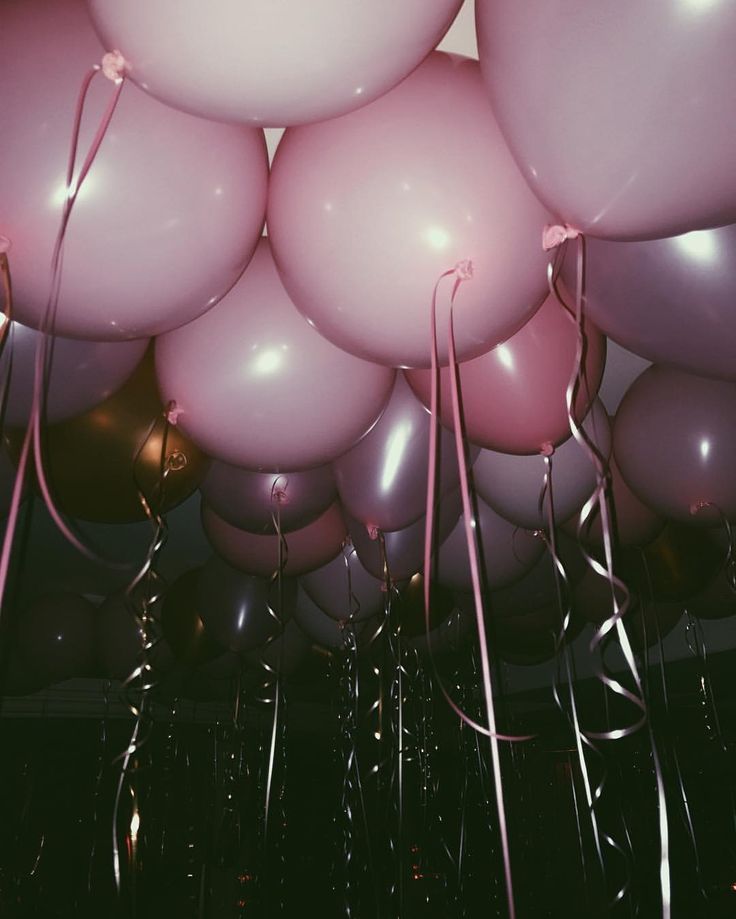 a bunch of pink and white balloons floating in the air