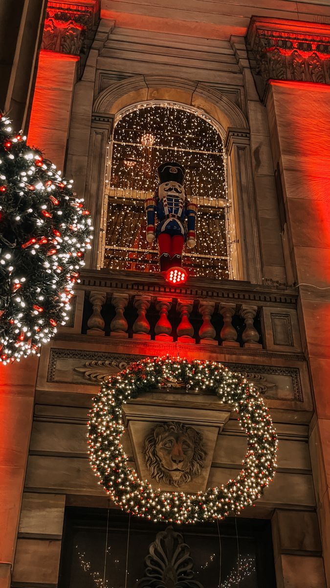 a large building with christmas lights on it's windows and wreaths hanging from the front