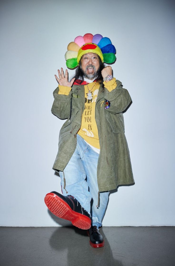 a man in a clown hat is standing with his hands up to the side and wearing red shoes