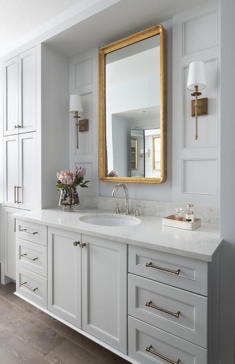 a large bathroom with white cabinets and gold framed mirror on the wall above the sink