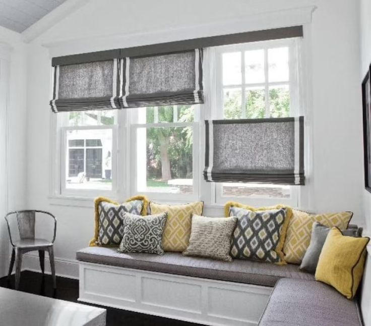 a living room filled with furniture and windows covered in shades of gray, yellow and white