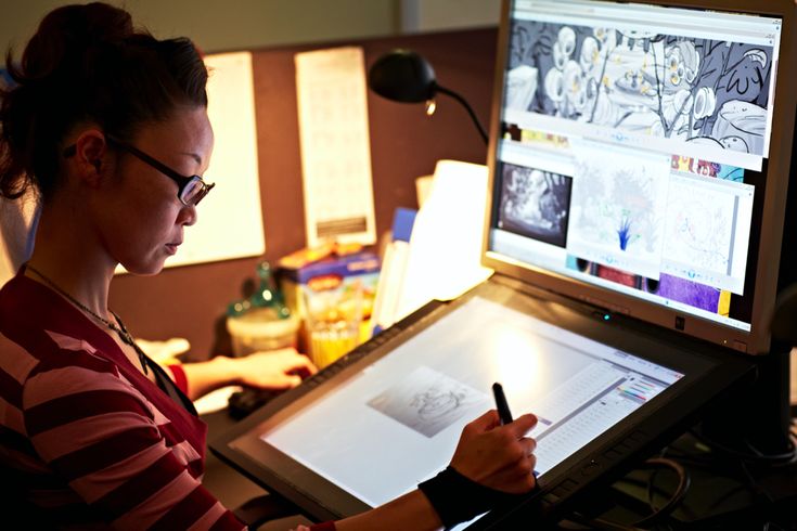 a woman sitting at a desk with a pen and paper in front of her computer screen