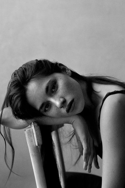 a black and white photo of a woman leaning on a chair