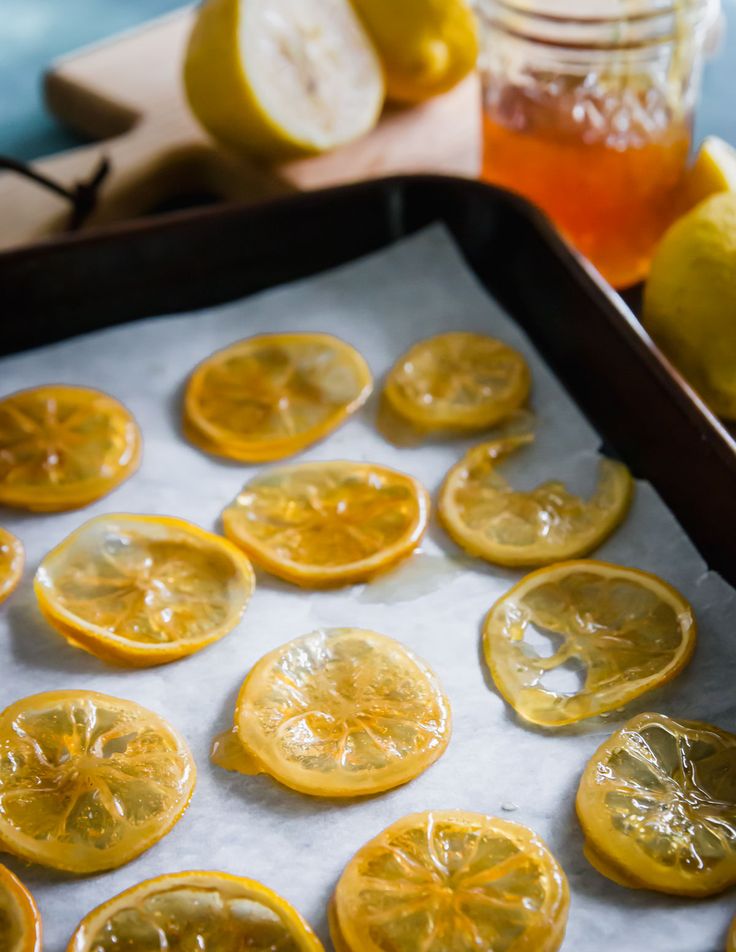 sliced lemons on a baking sheet with honey in the background