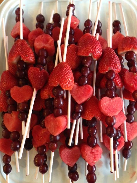 strawberries and cherries are arranged on skewers in the shape of hearts