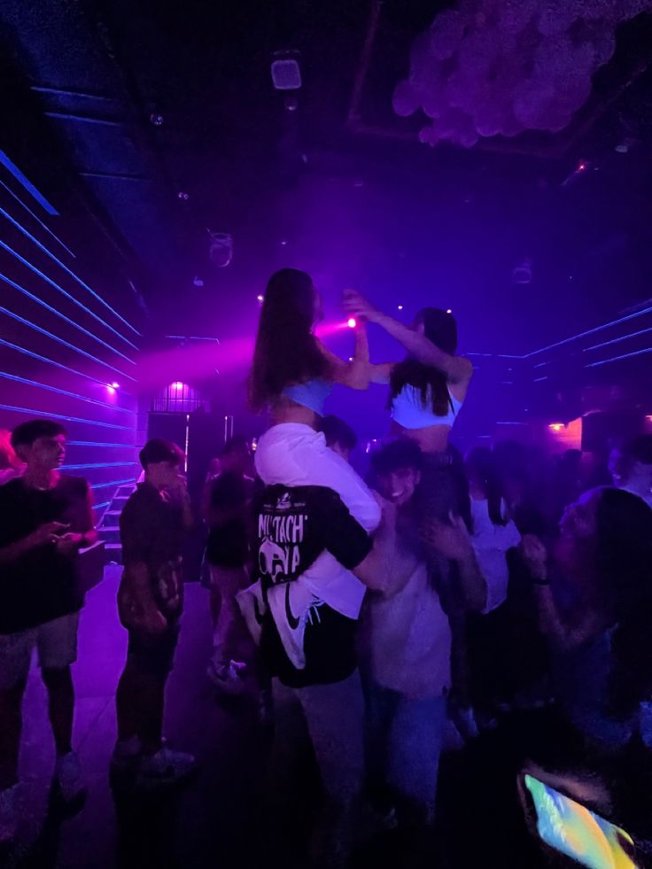 a group of people standing around in a room with purple lights on the walls and floor