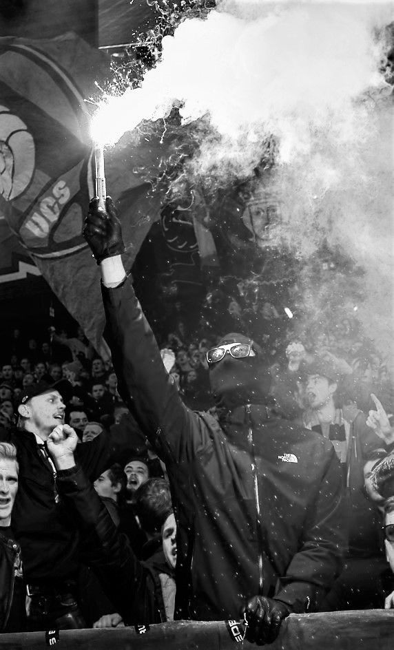 black and white photograph of a man holding a flarer in front of a crowd