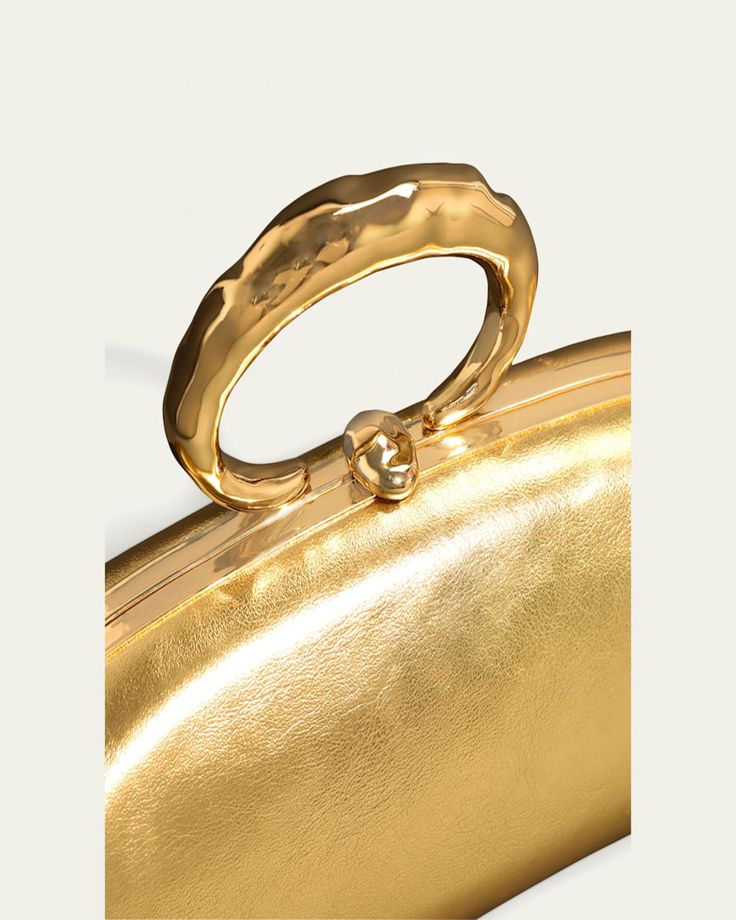 Alexis Bittar "Molton" bullet clutch bag in metallic laminated (high scratch resistance) Italian leather   14karat gold plated brass ring top handle    Can be worn as a top handle or clutch bag    Framed top with liftclasp closure    Lining: PU   Approx. 4"H x 3.5"W x 3.5"D   Item Weight (Lbs.): 1.0   Wipe clean   Imported Formal Gold Bag With Gold-tone Logo Plaque, Luxury Gold Clutch With Gold-tone Hardware, Luxury Gold Top Handle Evening Bag, Chic Metal Clutch For Formal Occasions, Chic Metal Clutch For Formal Events, Luxury Clutch With Gold-tone Hardware For Events, Chic Formal Clutch With Gold-tone Logo Plaque, Gold Evening Bags With Metal Hardware, Modern Gold Clutch For Evening