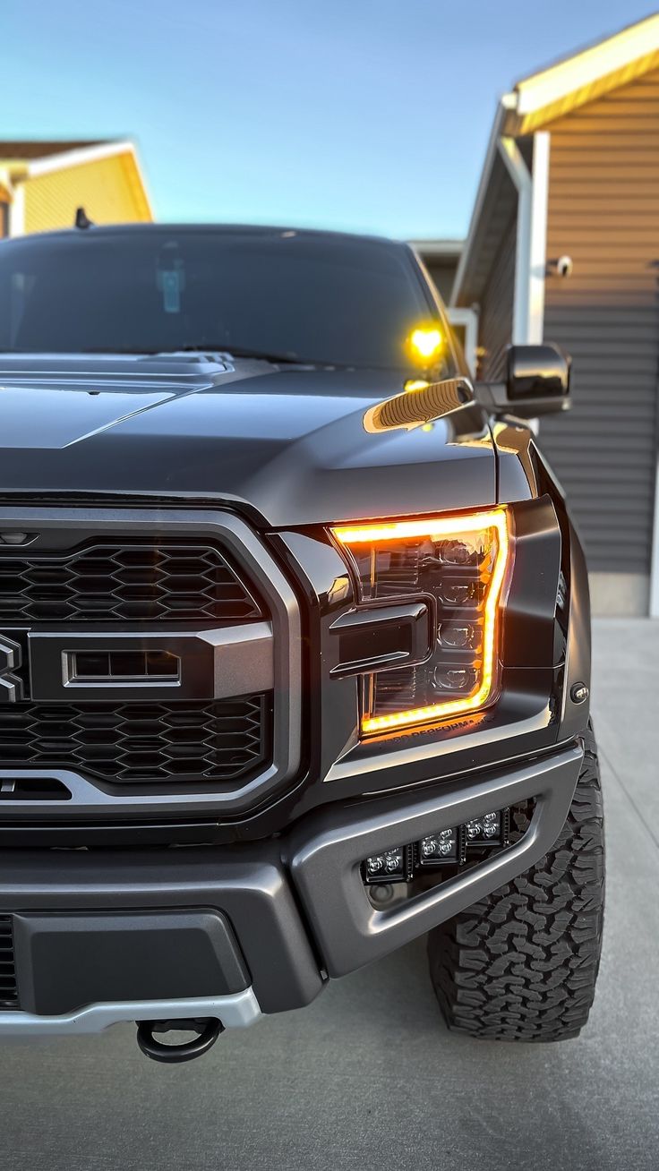 the front end of a black truck with its lights on