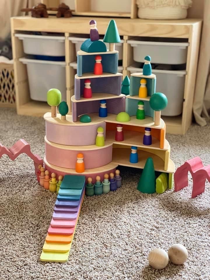 a toy house made out of wooden blocks and other toys on the floor in a playroom